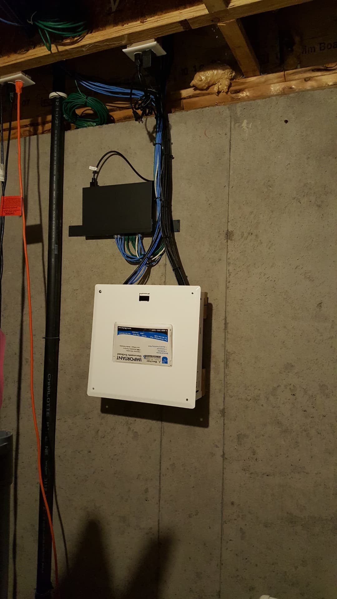 Finished basement cabling cleanup with organized data lines, network equipment, and a closed structured media enclosure
