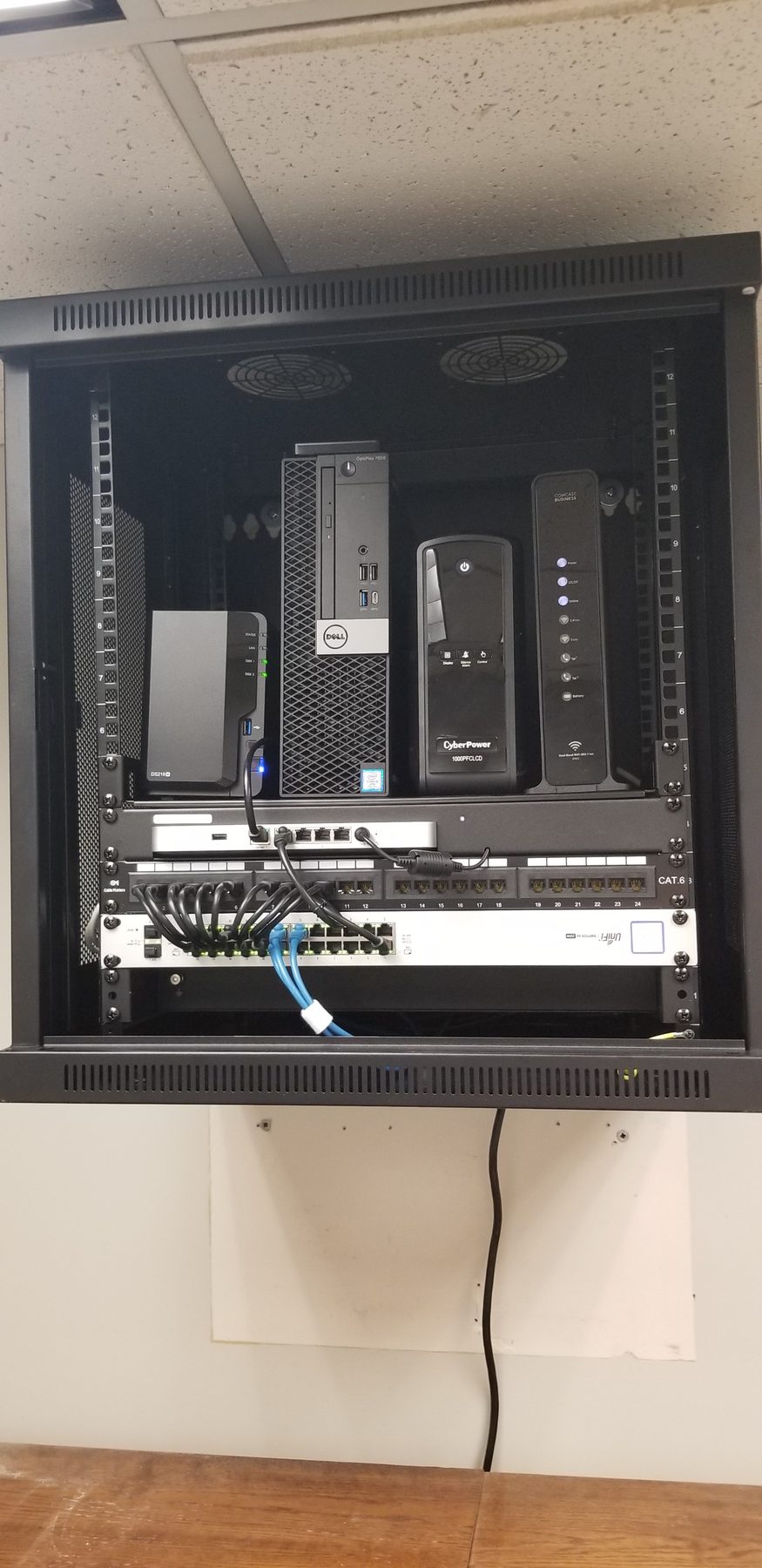 Open high-mounted office network cabinet containing network equipment, local storage, and battery backup