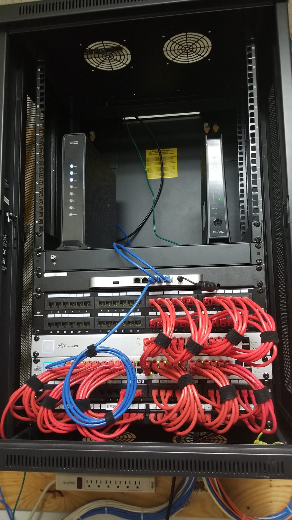 Open commercial network cabinet with organized patch cords, switching, and dual internet equipment