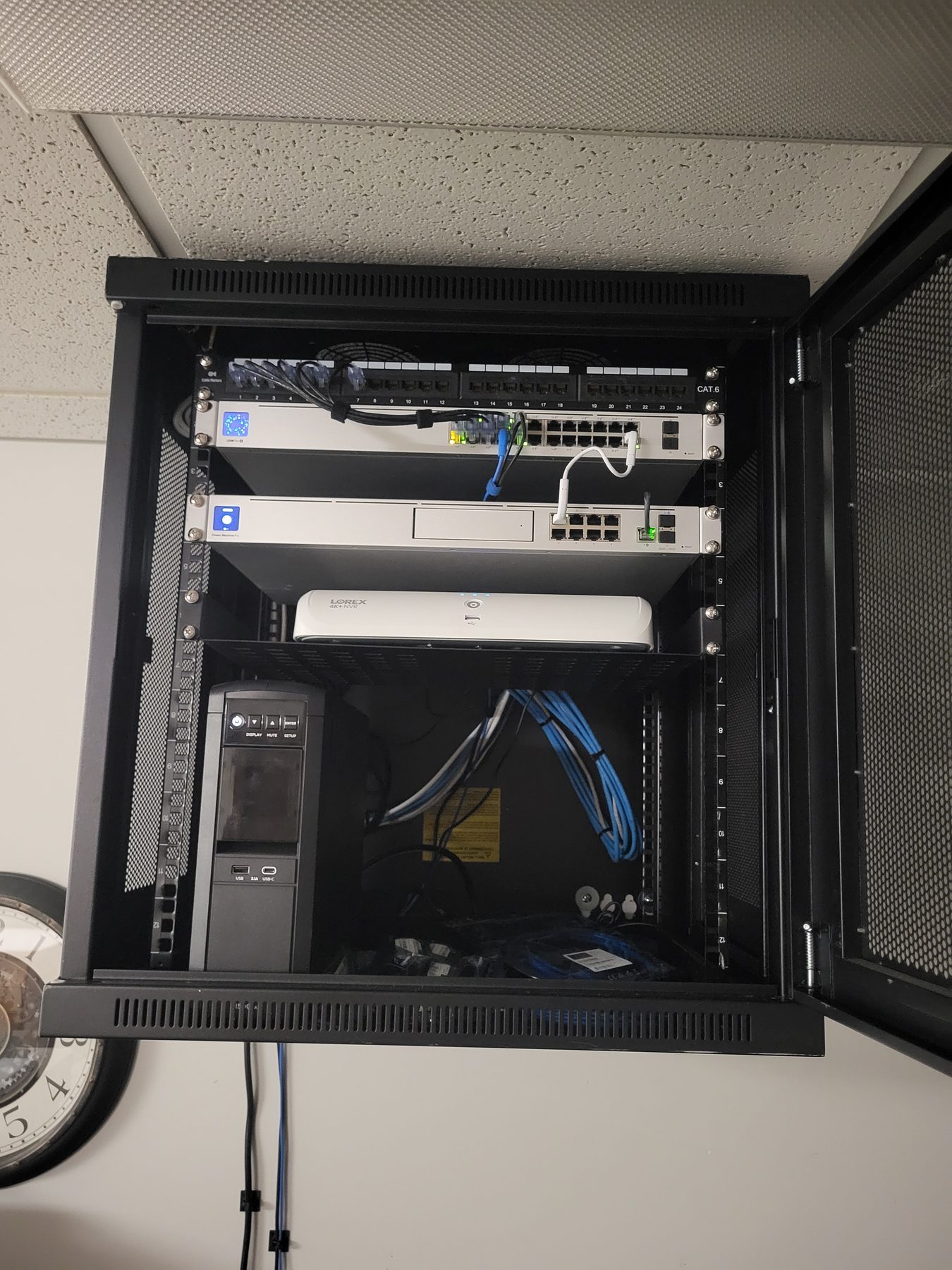 Open commercial cabinet with network gateway, PoE switch, video recorder, and battery backup