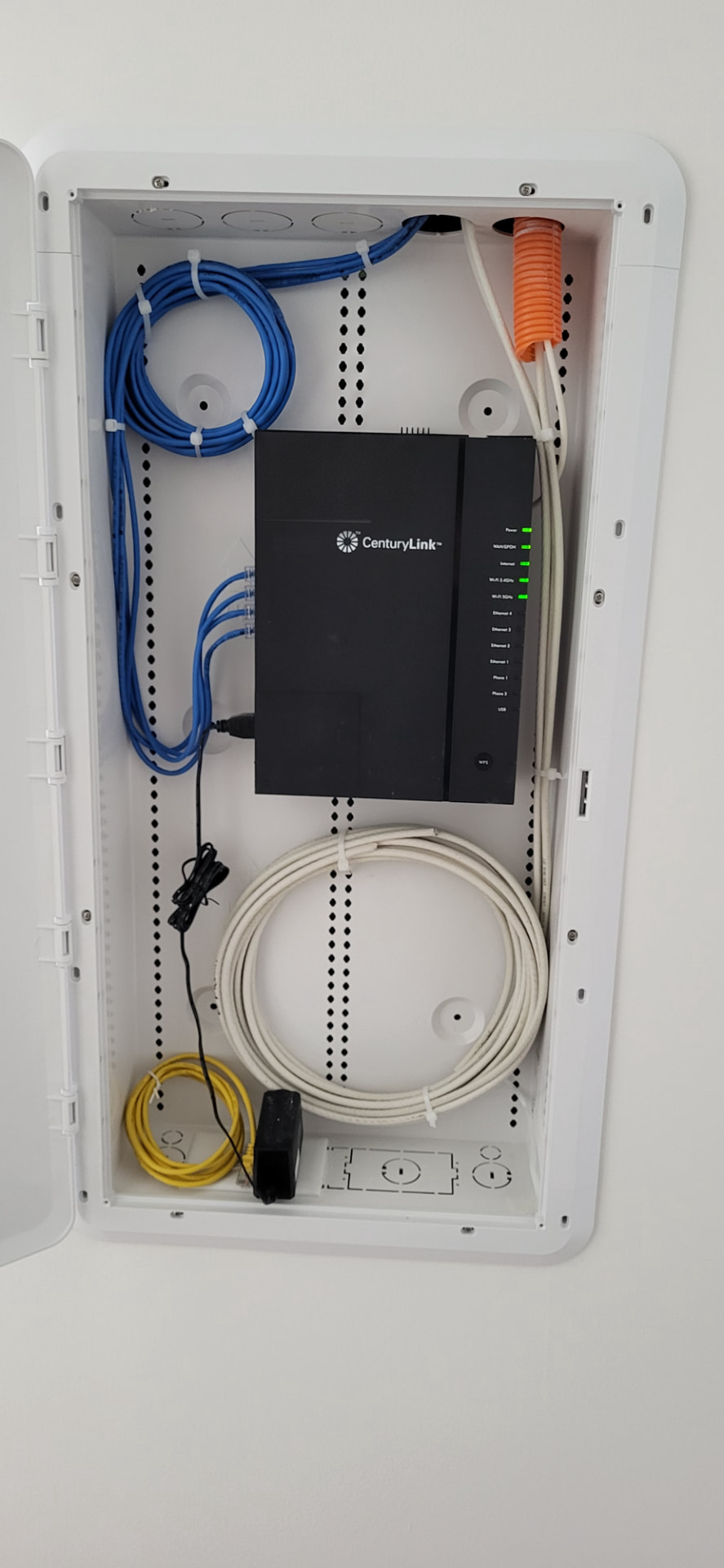 Open residential structured media enclosure with organized blue data cabling and internet equipment