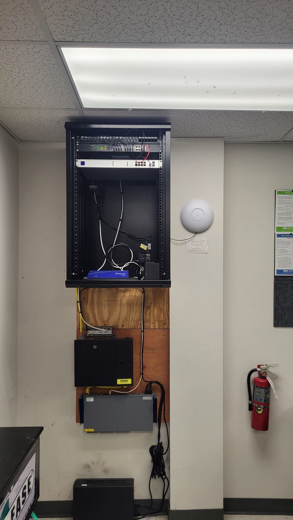 Open wall-mount rack showing the switch and rack-mounted equipment with cabling dressed to the sides