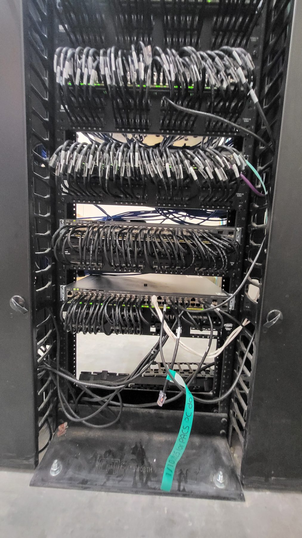 Rear view of the rack showing horizontal cable management bars with labeled station cabling combed into rows