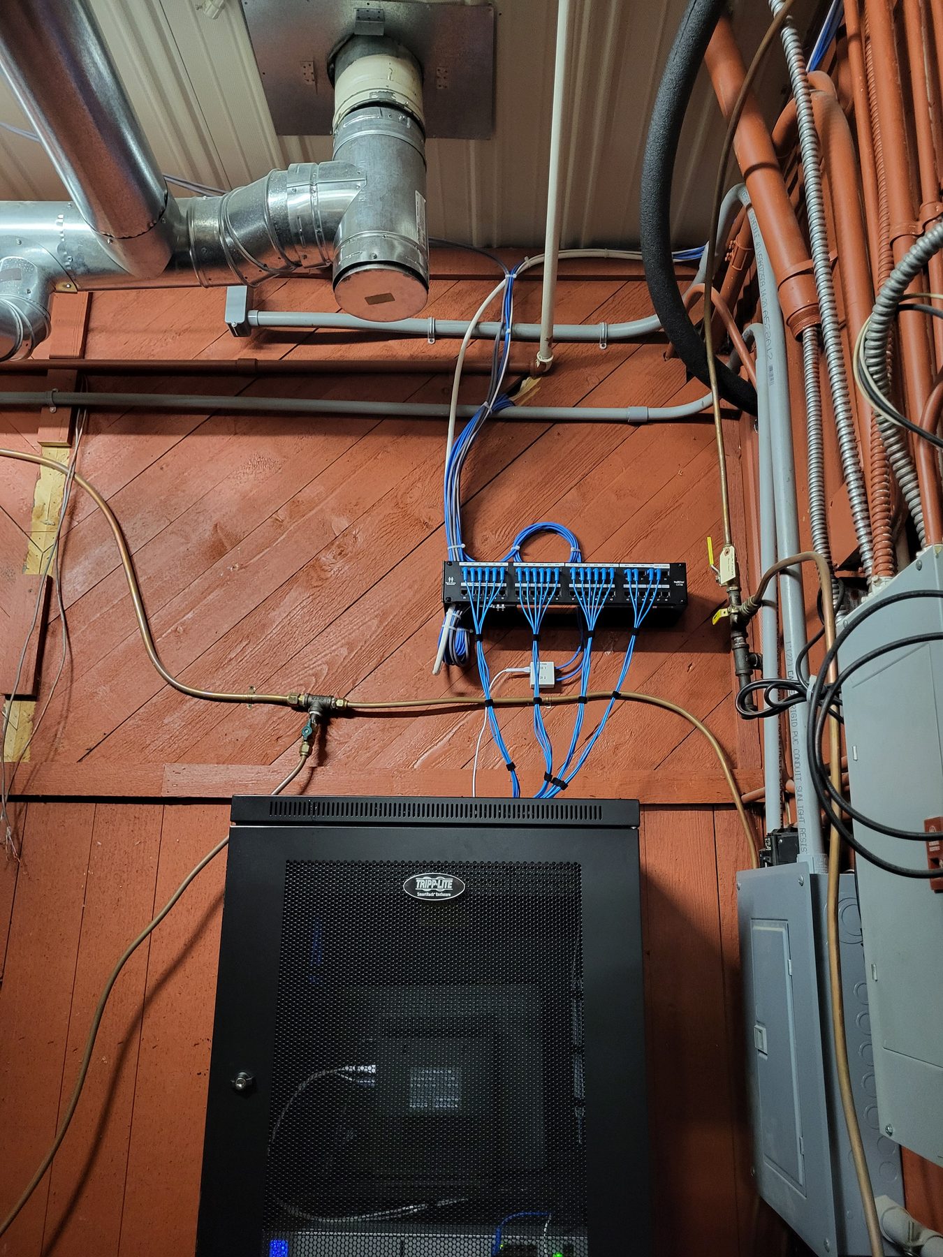 Patch panel and network cabinet installed beside metal ductwork and conduit runs in a utility space