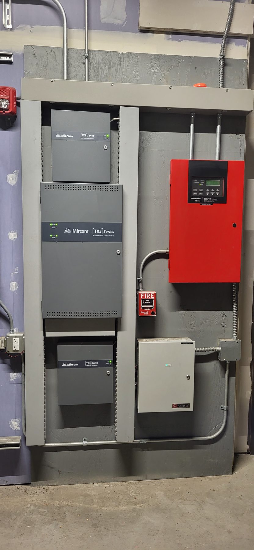 Wall-mounted access control and communication panels with conduit runs in a parking garage service area