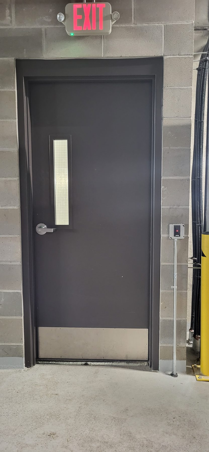 Second controlled steel door with a card reader and lit exit sign above the frame