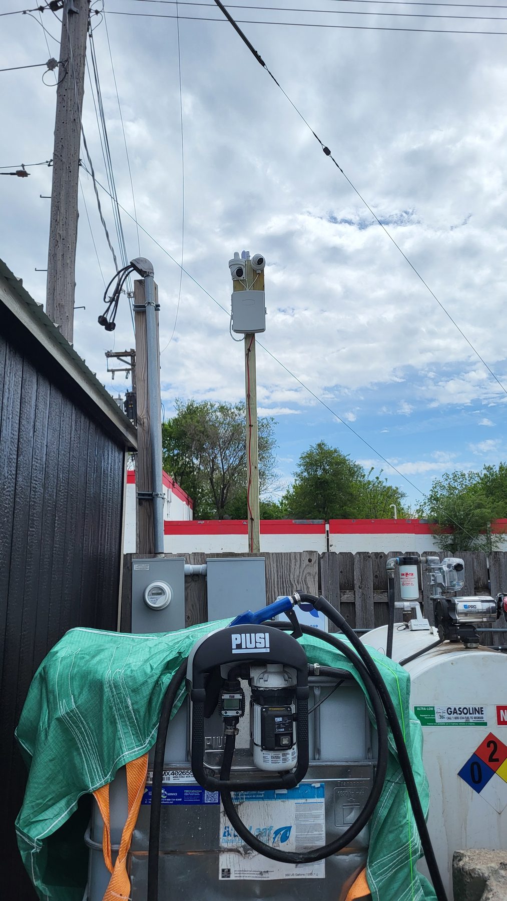 Upward view of a yard camera on its pole mount above a fuel pump and covered equipment